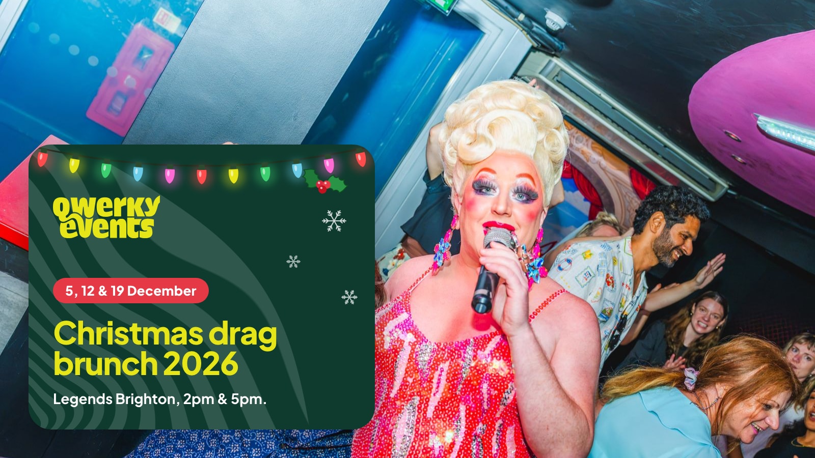 A drag queen singing to a table of guests waving fans at Legends Brighton